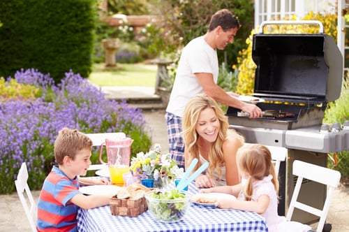 Family-Enjoying-Outdoor-Barbeque-In-Garden