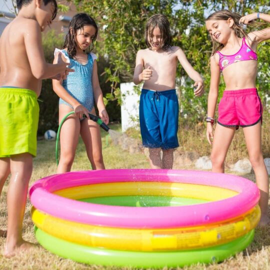 kids hanging around a kid pool filled with water