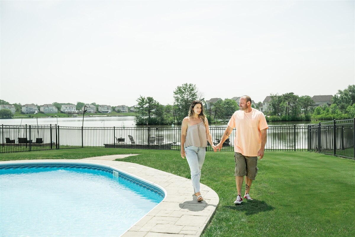 man and woman walking on the lawn next to their pool